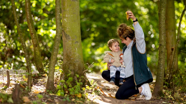Image shows a child and mum playing with autumn leaves